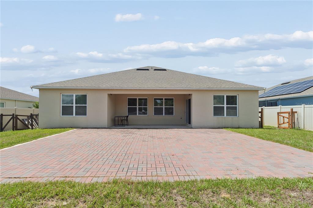 The rear exterior of a house features a paved patio, a covered lanai, and fencing — 515 AUBURN GROVE TERRACE, AUBURNDALE, FL