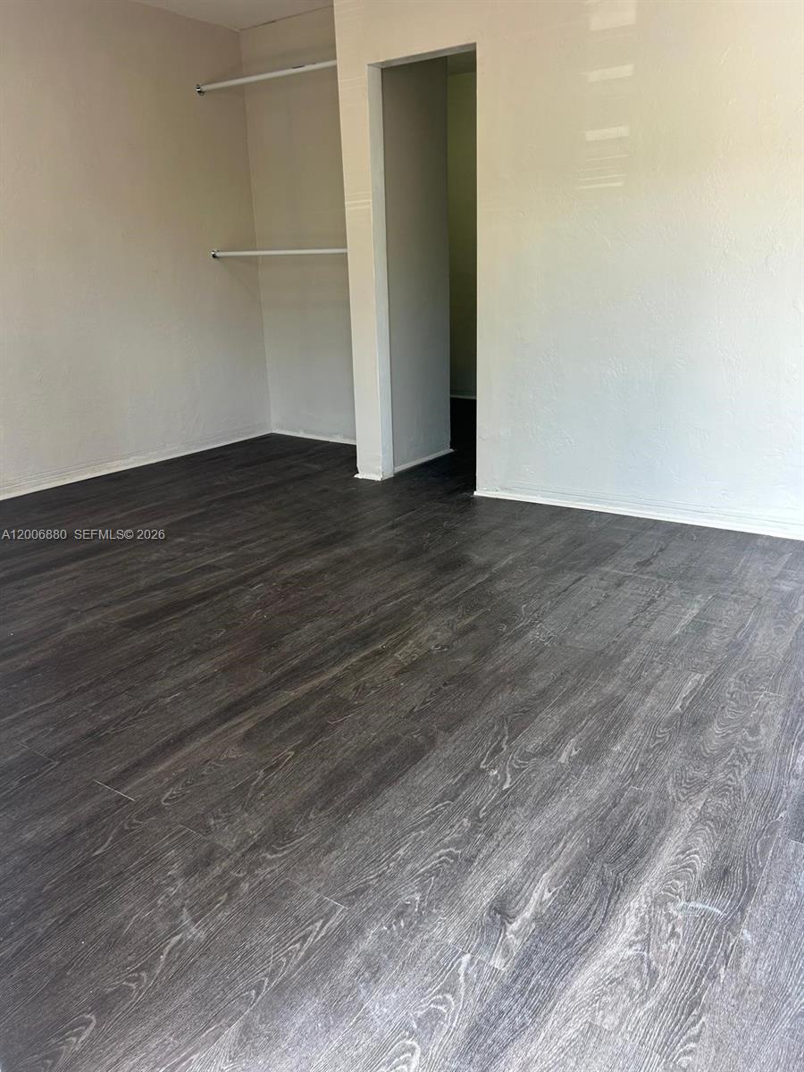 This room features dark wood-look flooring, white walls, and an open closet area — 1743 NW 15th St # 1743, Miami FL 33125, MIAMI, FL