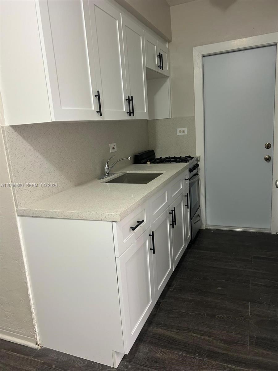A small kitchen features white cabinets, a light countertop, and dark wood-look flooring — 1743 NW 15th St # 1743, Miami FL 33125, MIAMI, FL