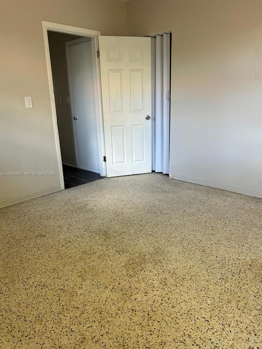 An empty room features beige speckled flooring, a white door, and an open doorway — 1743 NW 15th St # 1743, Miami FL 33125, MIAMI, FL