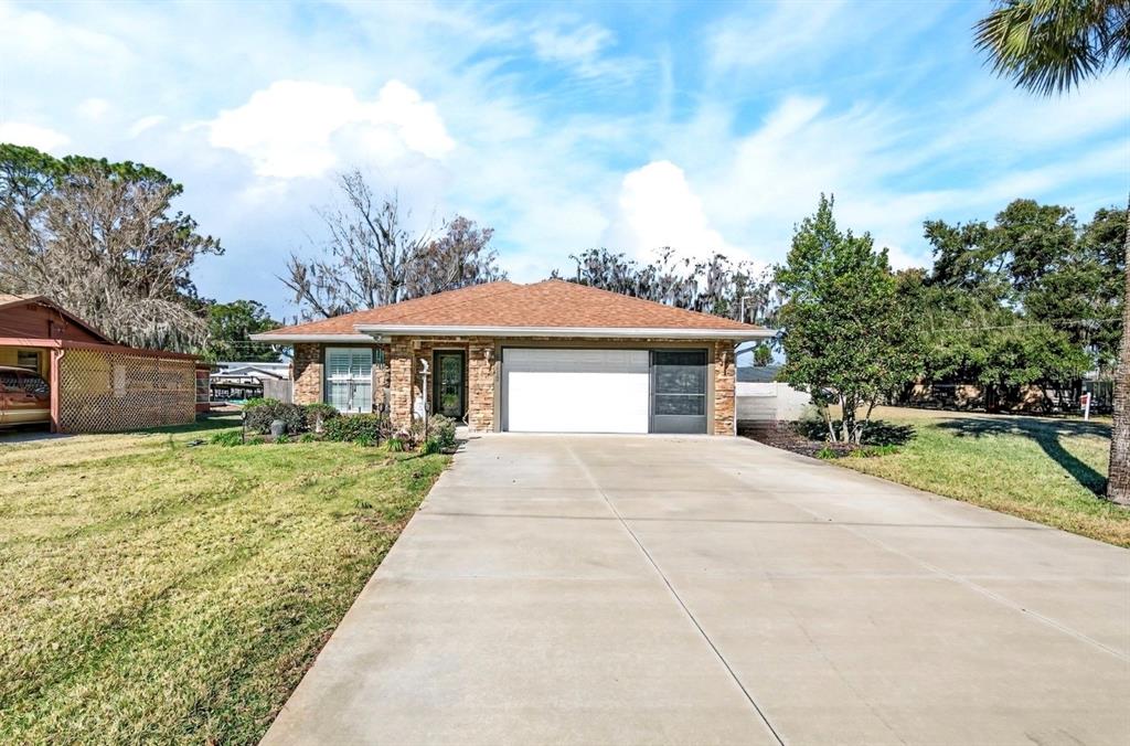 A single-story brick house with a concrete driveway and a two-car garage — 35653 CALLA COURT, LEESBURG, FL