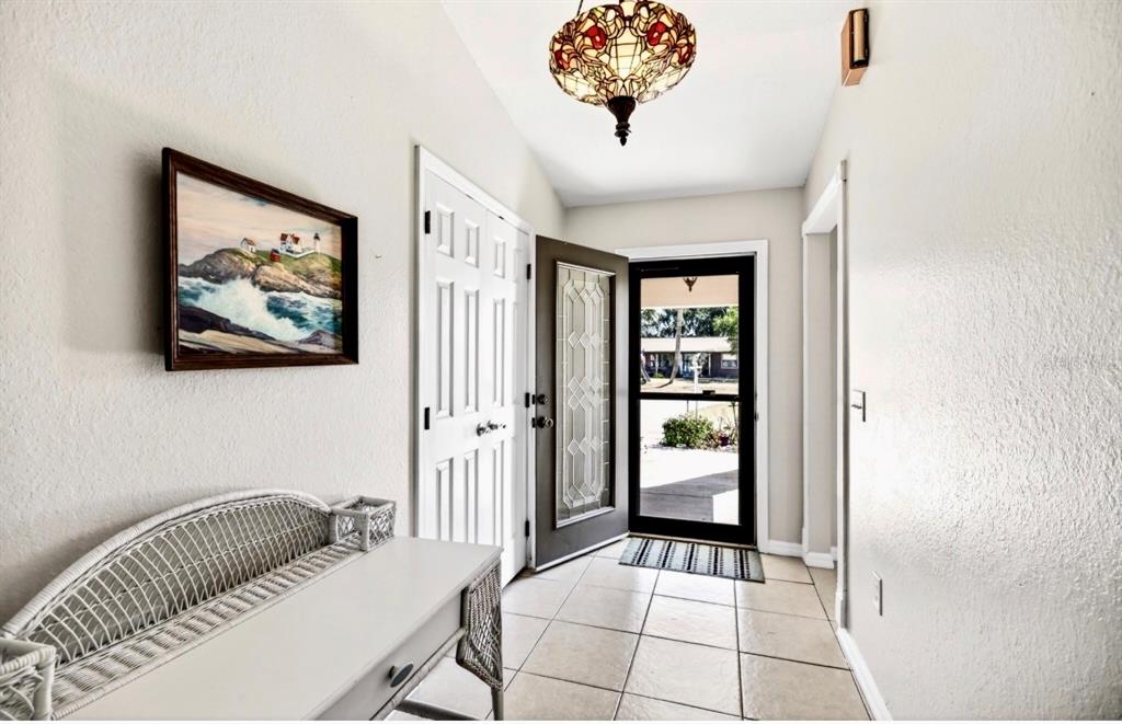 An entryway features a tiled floor, a stained-glass pendant light, and a white wicker bench — 35653 CALLA COURT, LEESBURG, FL
