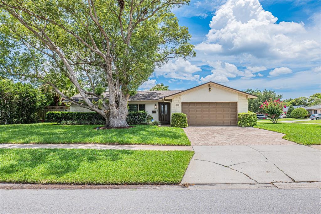 A single-story house with a large tree, a paved driveway, and a two-car garage — 741 BROOKSIDE ROAD, MAITLAND, FL