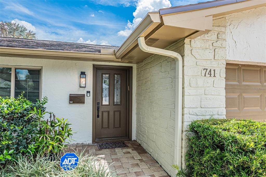 The exterior of a house features a brown front door, stone siding, and a gutter — 741 BROOKSIDE ROAD, MAITLAND, FL