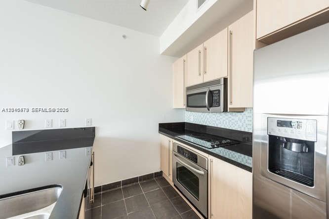 A modern kitchen features light wood cabinets, stainless steel appliances, and black granite countertops — 79 SW 12th St, Miami FL 33130, MIAMI, FL