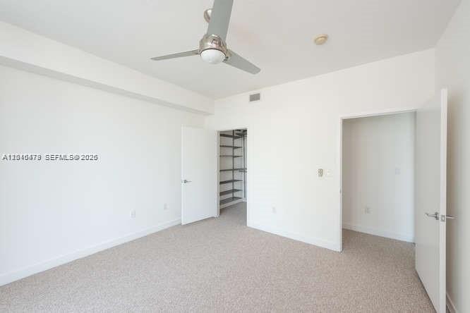 An empty bedroom with beige carpet, white walls, a ceiling fan, and two open doorways — 79 SW 12th St, Miami FL 33130, MIAMI, FL