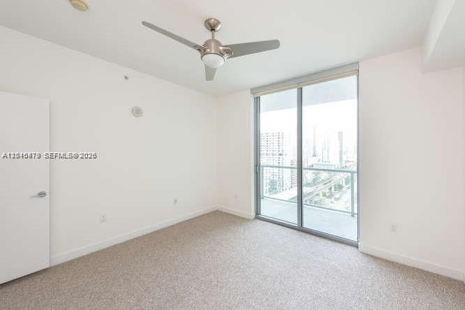 An empty bedroom features beige carpet, a ceiling fan, and a sliding glass balcony door — 79 SW 12th St, Miami FL 33130, MIAMI, FL