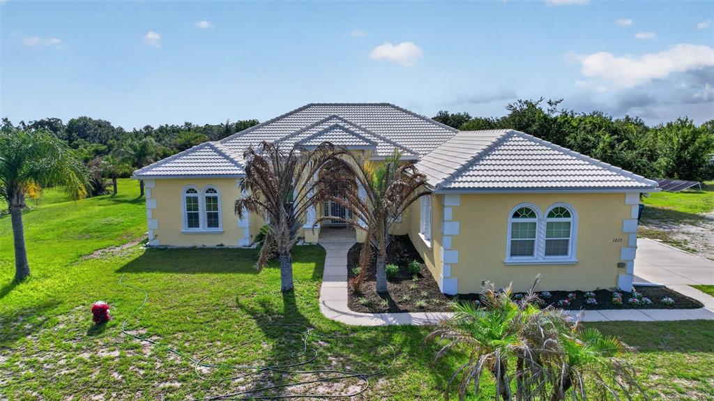 A yellow single-story house with a tiled roof and a front walkway sits on grass — 1210 408TH COURT E, MYAKKA CITY, FL