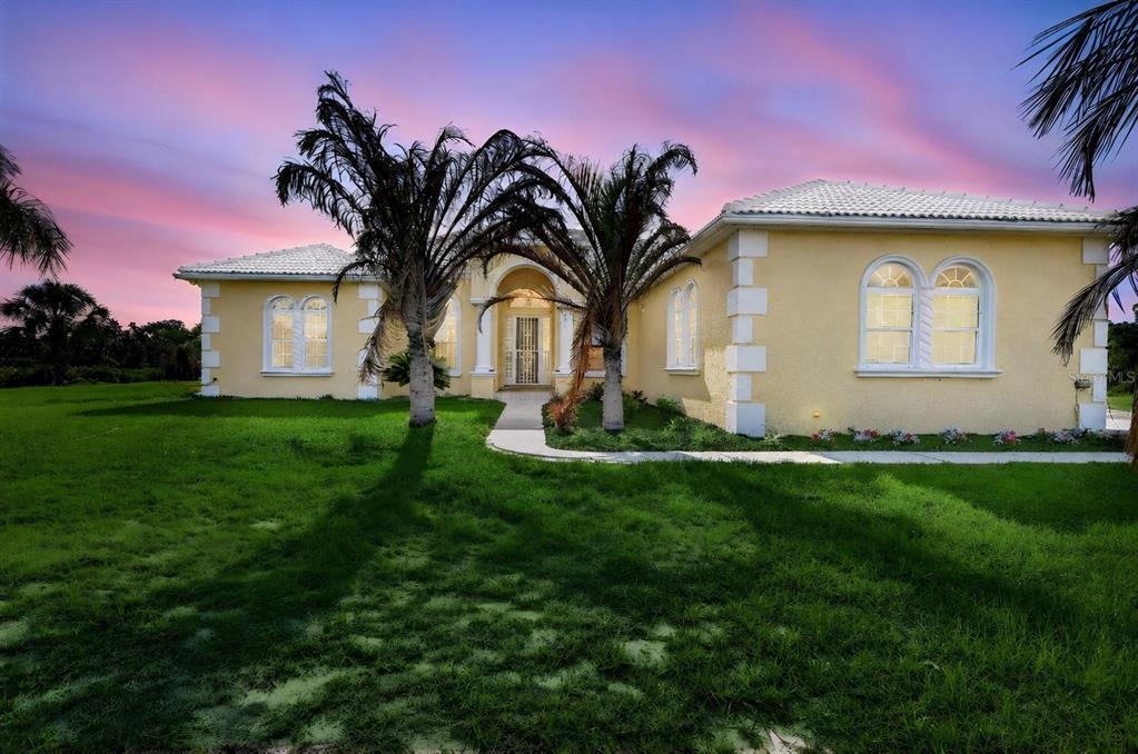 A yellow single-story house with a tiled roof and palm trees under a sunset sky — 1210 408TH COURT E, MYAKKA CITY, FL