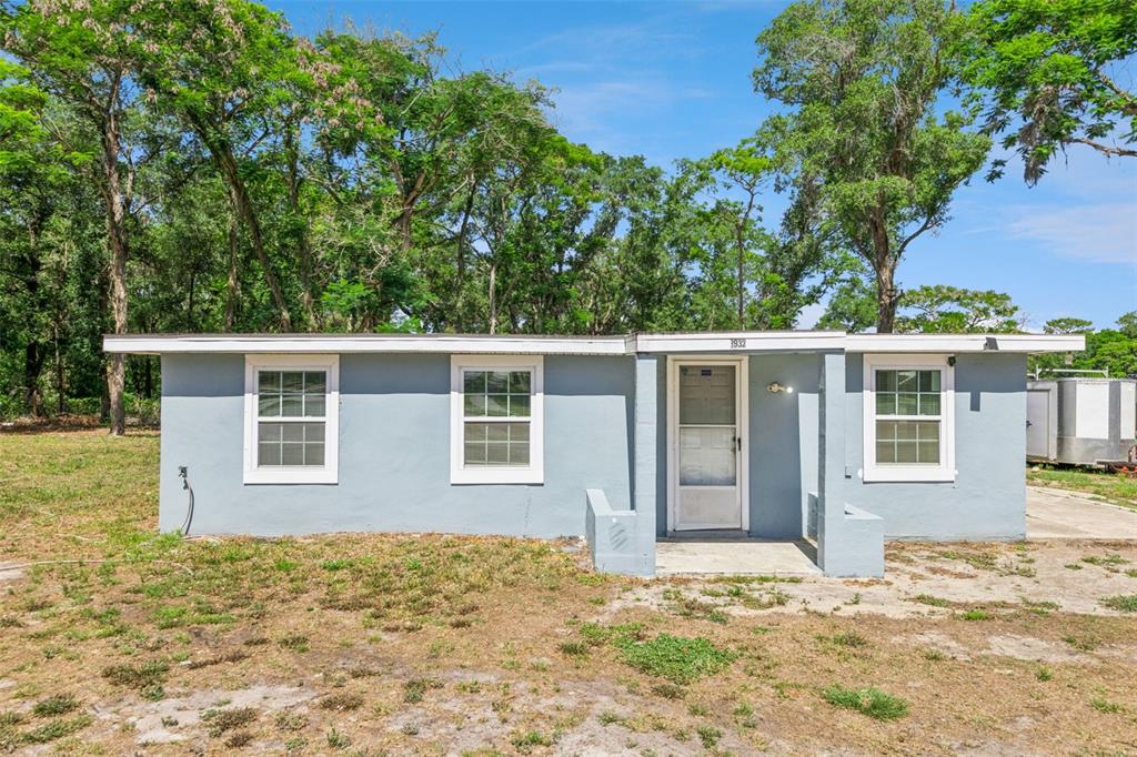 A single-story light blue house with a flat roof and three windows sits on grass — 3932 WHITE HERON DRIVE, ORLANDO, FL