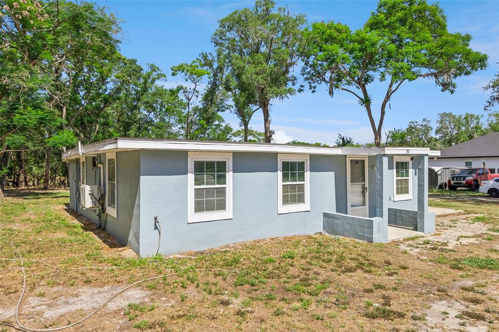 A single-story gray house with a flat roof sits on a grassy lot with trees — 3932 WHITE HERON DRIVE, ORLANDO, FL