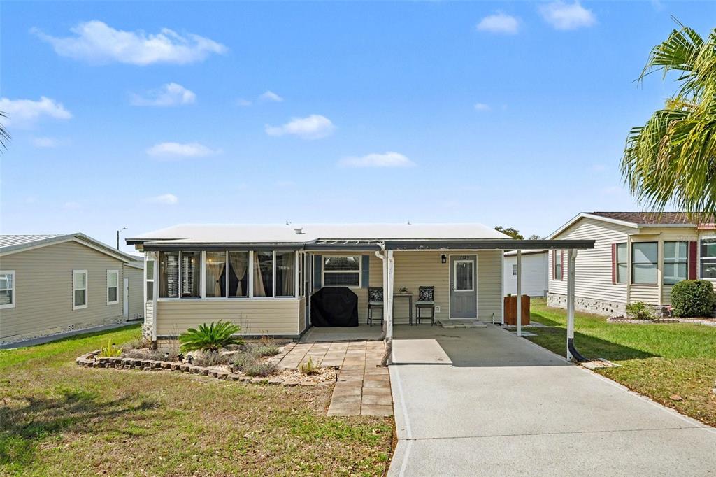 A single-story manufactured home features a front porch, a carport, and a concrete driveway — 7123 SIESTA STREET, ZEPHYRHILLS, FL