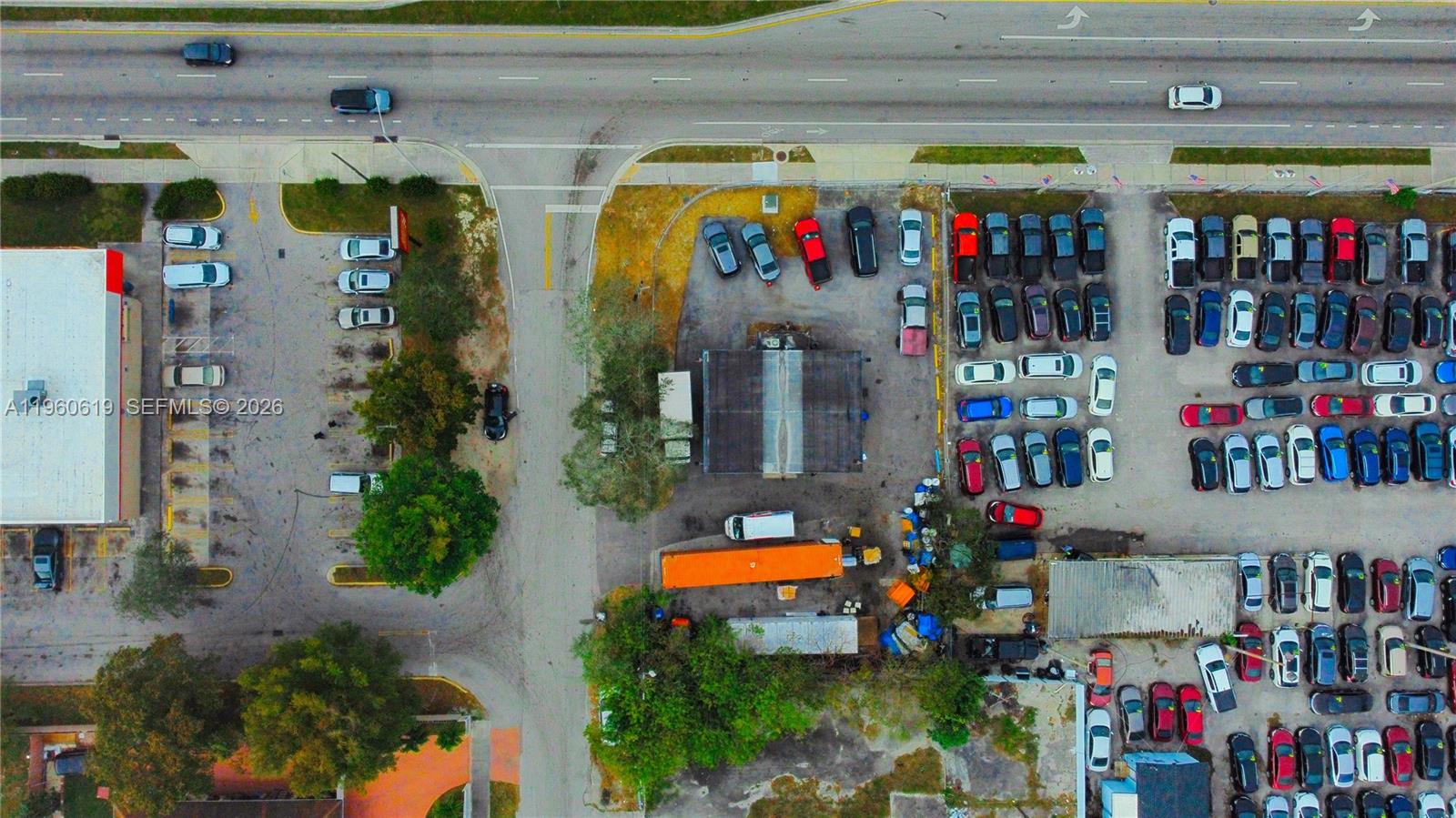 This aerial view shows a commercial property with a parking lot filled with many cars — 9301 NW 27th Ave, Miami FL 33147, MIAMI, FL