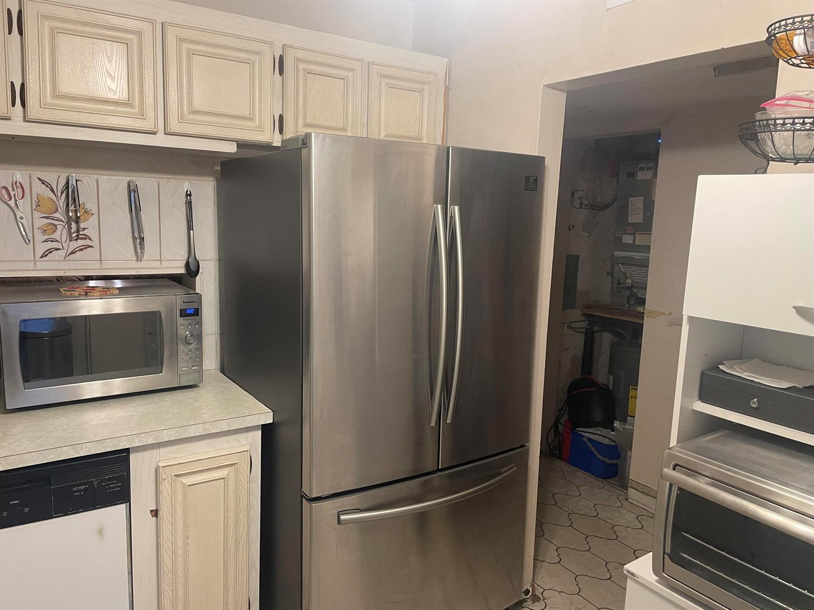 A kitchen features stainless steel appliances, off-white cabinets, and a doorway leading to a utility area — 1101 NW 58th Terrace # 404, Sunrise FL 33313, SUNRISE, FL
