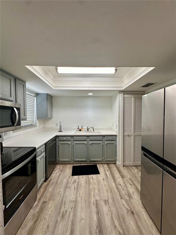A kitchen features gray cabinets, stainless steel appliances, white countertops, and light wood-look flooring — 223 NW 34TH STREET, GAINESVILLE, FL