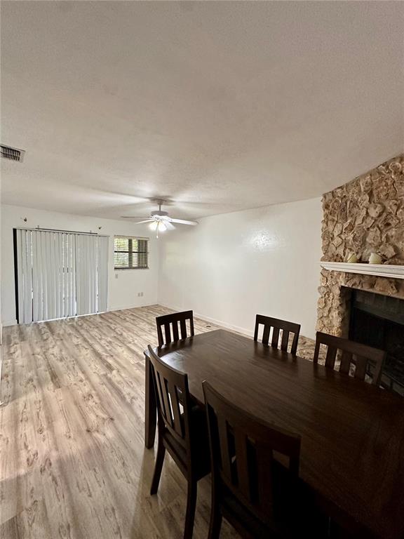 A dining area with a wooden table and chairs next to a stone fireplace — 223 NW 34TH STREET, GAINESVILLE, FL
