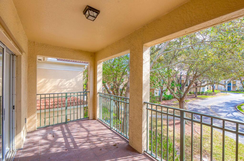 A covered balcony with tile flooring, metal railings, and a view of trees and a road — 2400 Centergate Dr # 202, Miramar FL 33025, MIRAMAR, FL