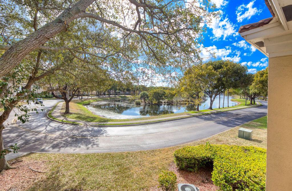 An elevated view of a curved road, a small pond, and trees under a blue sky — 2400 Centergate Dr # 202, Miramar FL 33025, MIRAMAR, FL