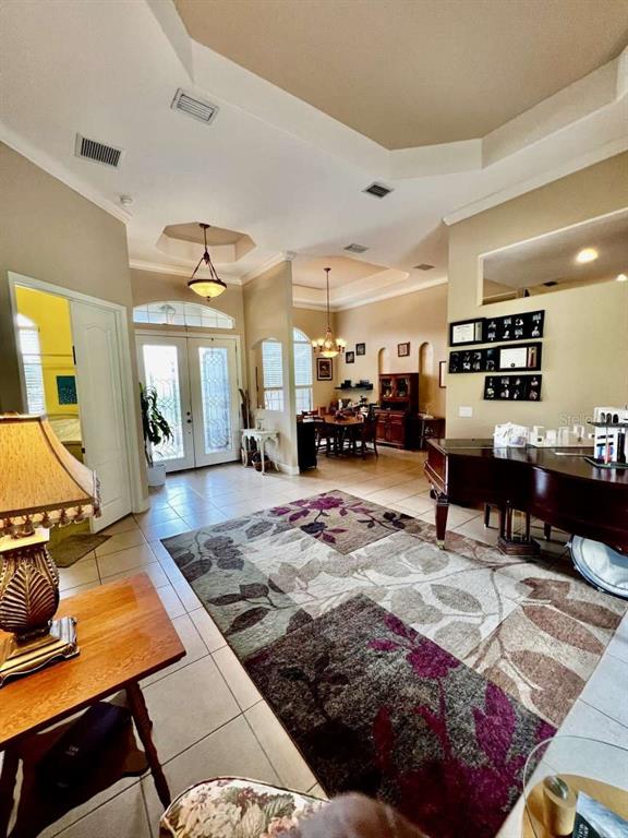 A living room with a grand piano, tile floors, and a large floral area rug — 16325 MAGNOLIA BLUFF DRIVE, MONTVERDE, FL