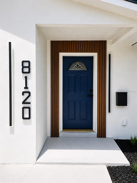 A blue front door is framed by wood slats on a white exterior wall — 8120 7TH STREET N, ST PETERSBURG, FL