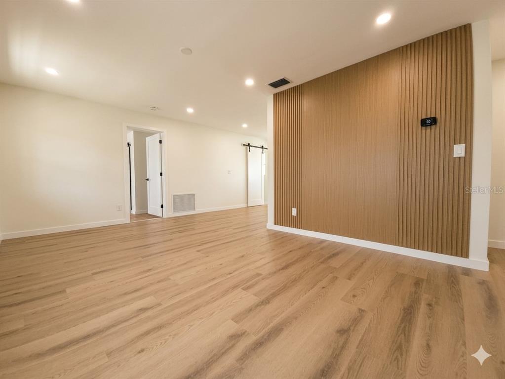 An interior room features light wood-look flooring and a decorative vertical wood slat accent wall — 8120 7TH STREET N, ST PETERSBURG, FL
