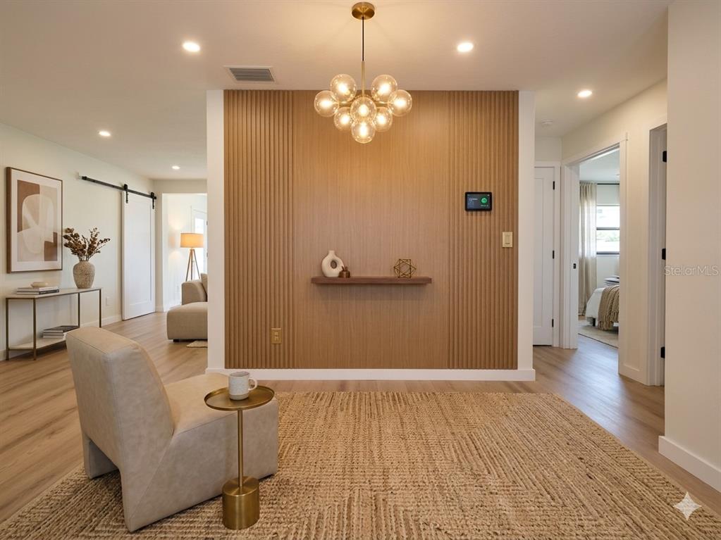 A living area features a wood-slatted accent wall with a floating shelf and modern chandelier — 8120 7TH STREET N, ST PETERSBURG, FL