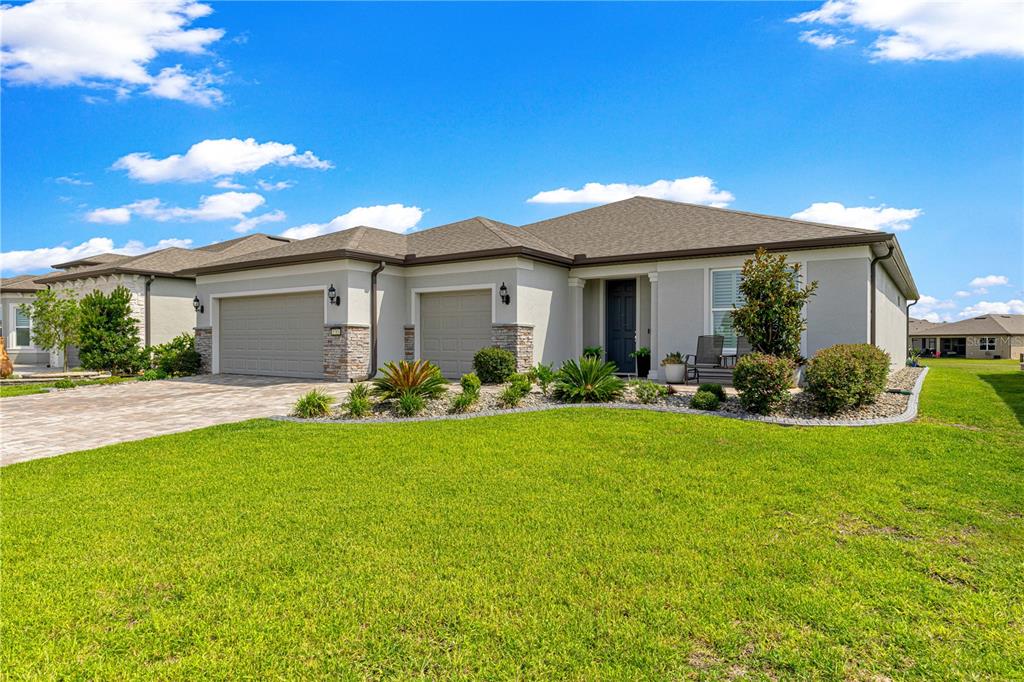 A single-story house with a two-car garage, stone accents, and a landscaped front yard — 8783 SW 57TH PLACE ROAD, OCALA, FL