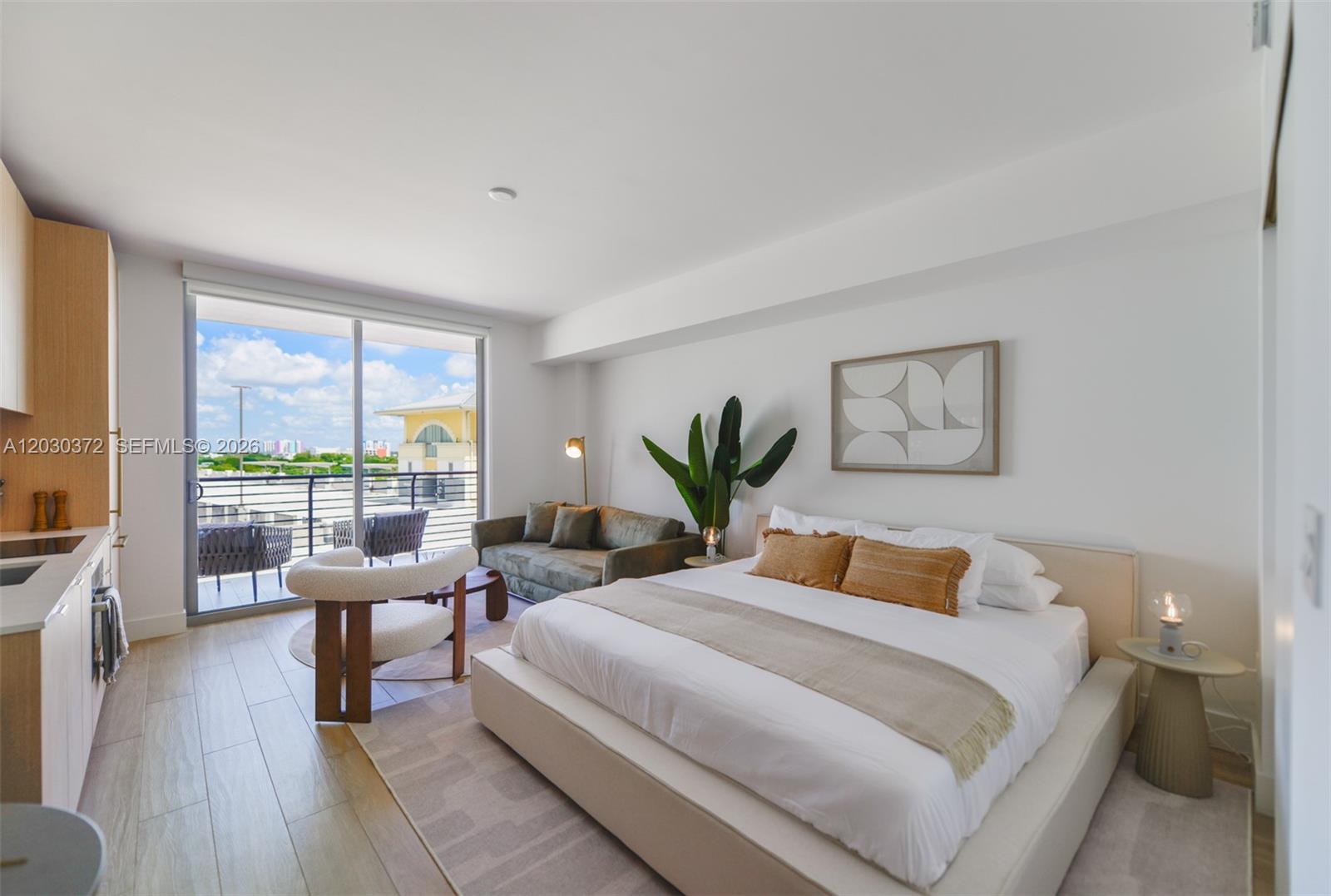 A modern bedroom features a bed, a small sofa, a chair, and a balcony view — 90 NE 32nd Street # 618, Miami FL 33127, MIAMI, FL