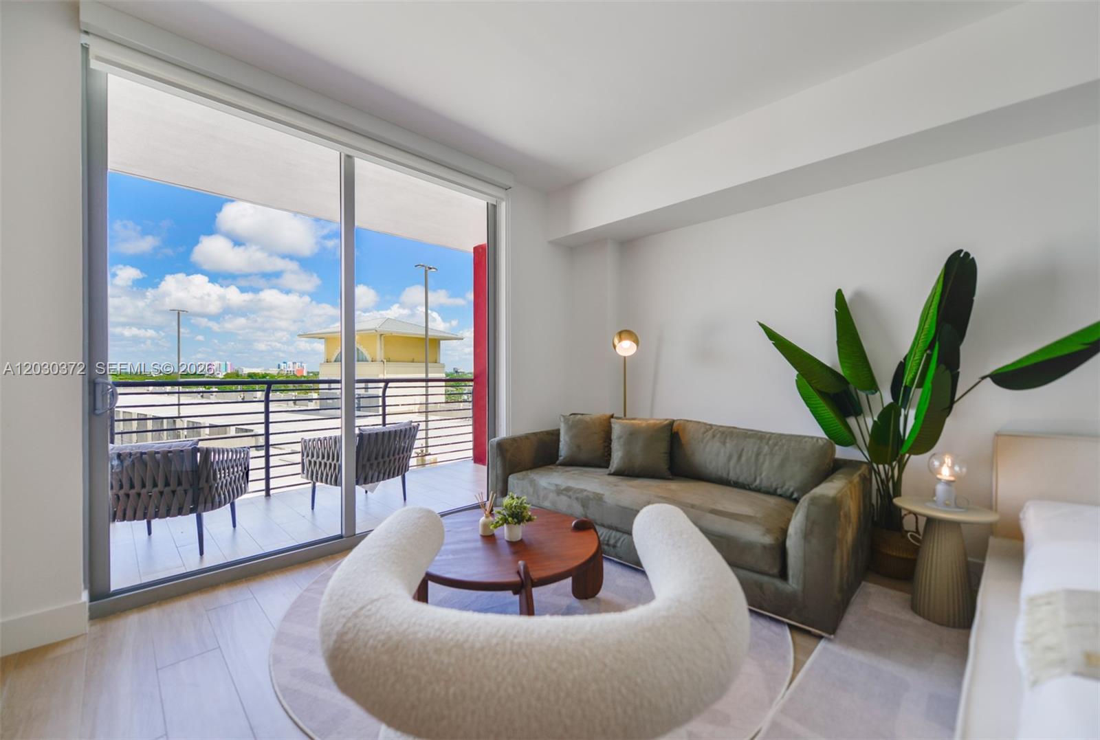 A living room features a green sofa, a circular coffee table, and a balcony view — 90 NE 32nd Street # 618, Miami FL 33127, MIAMI, FL