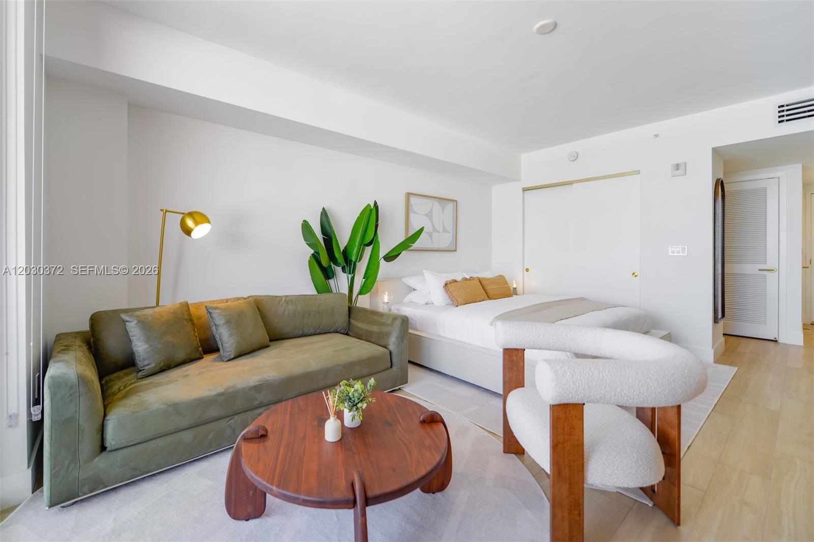 A studio apartment features a green sofa, a round wooden coffee table, and a bed — 90 NE 32nd Street # 618, Miami FL 33127, MIAMI, FL