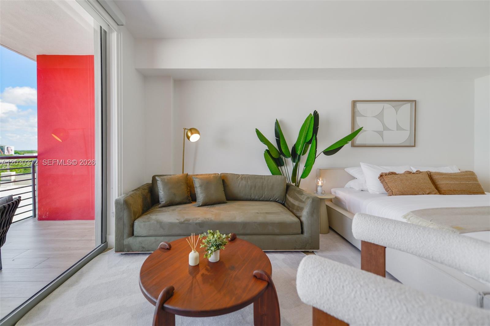 A bedroom features a green sofa, a round wooden coffee table, and a private balcony — 90 NE 32nd Street # 618, Miami FL 33127, MIAMI, FL