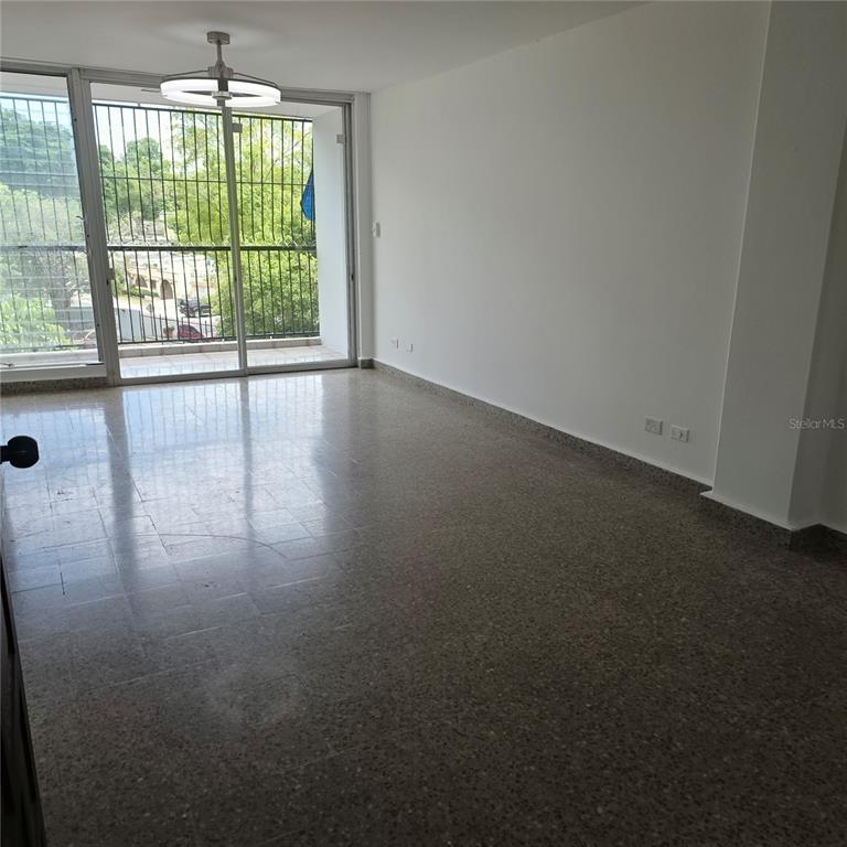 An empty room features speckled tile flooring, white walls, and a sliding glass balcony door — 424 CALLE ENSENADA UNIT 307, SAN JUAN, PR