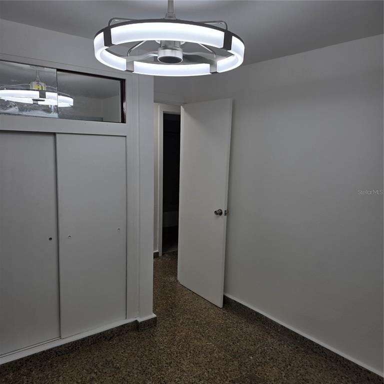 A room with a modern circular light fixture, white walls, sliding closet doors, and terrazzo flooring — 424 CALLE ENSENADA UNIT 307, SAN JUAN, PR