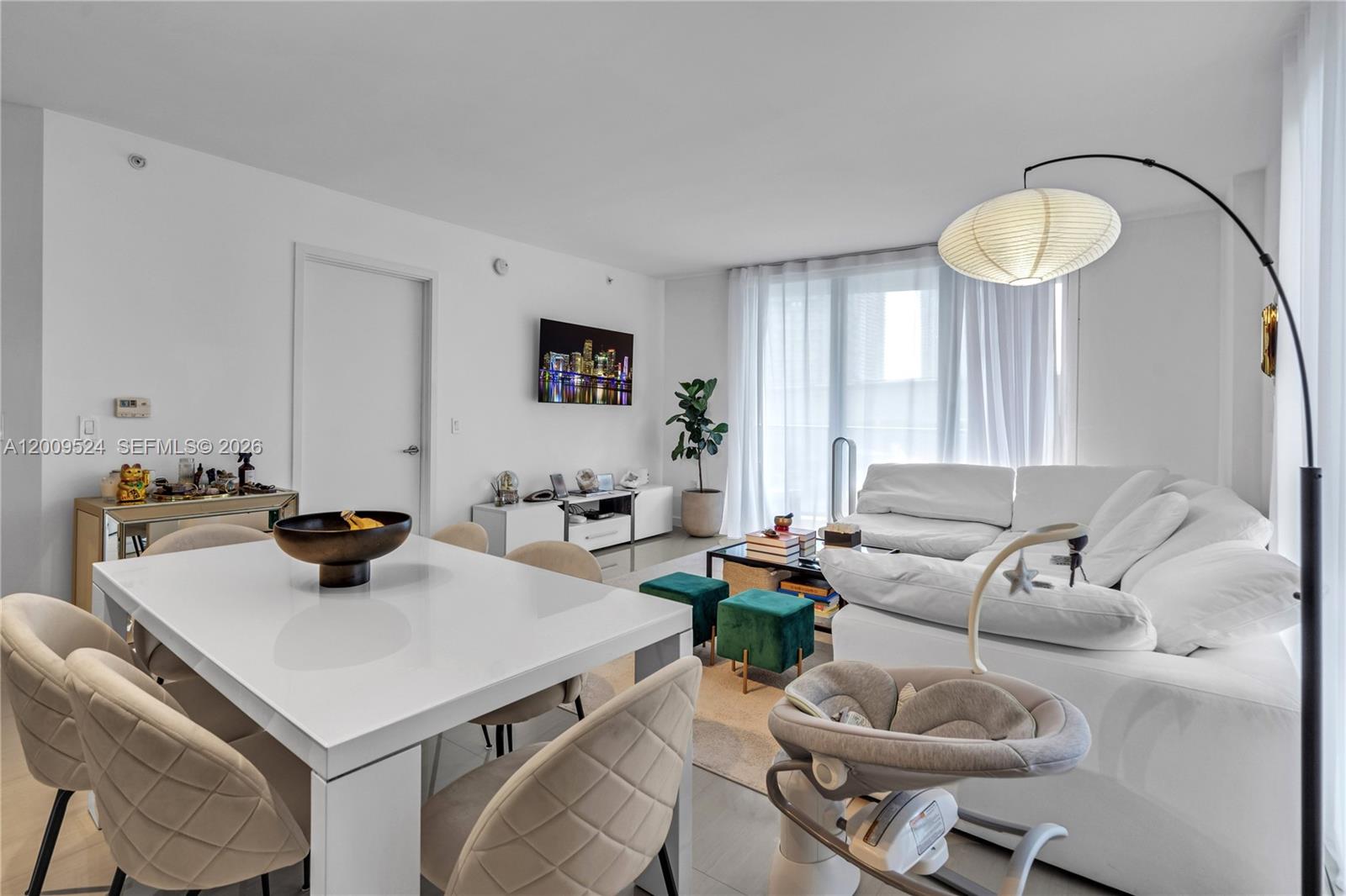 A bright, modern living and dining area features white furniture, a sectional sofa, and floor-to-ceiling curtains — 31 SE 6th St # 702, Miami FL 33131, MIAMI, FL