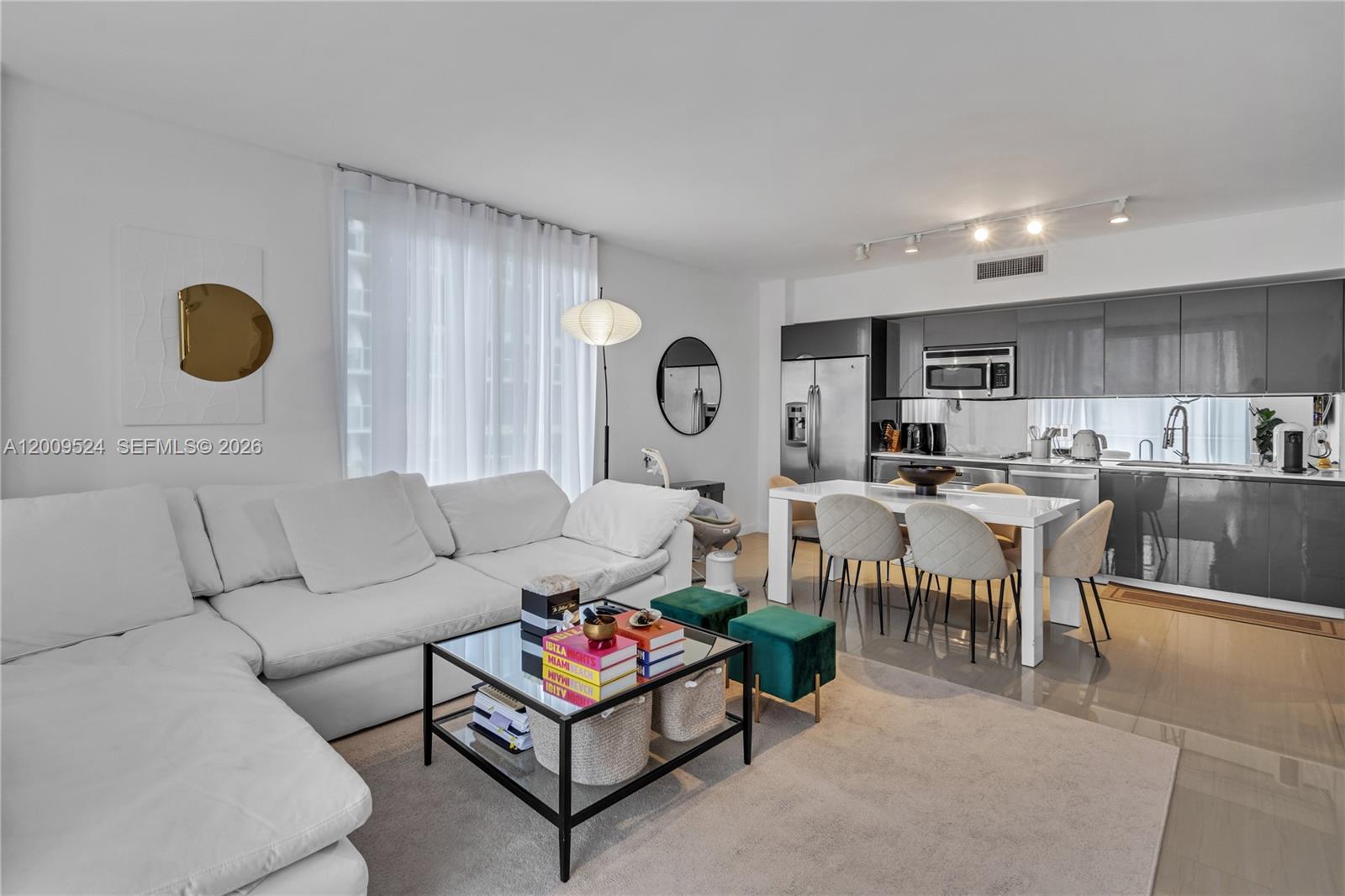 A living room and kitchen area with a white sectional sofa and dining table — 31 SE 6th St # 702, Miami FL 33131, MIAMI, FL