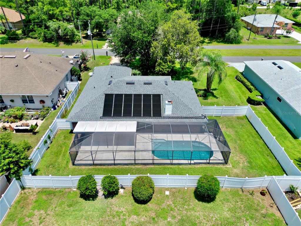 An aerial view of a house with a screened-in pool and solar panels on the roof — 12 EASTMOOR LANE, PALM COAST, FL