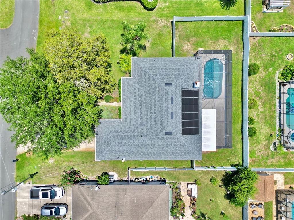 An aerial view shows a house with a gray roof, solar panels, and a screened pool — 12 EASTMOOR LANE, PALM COAST, FL