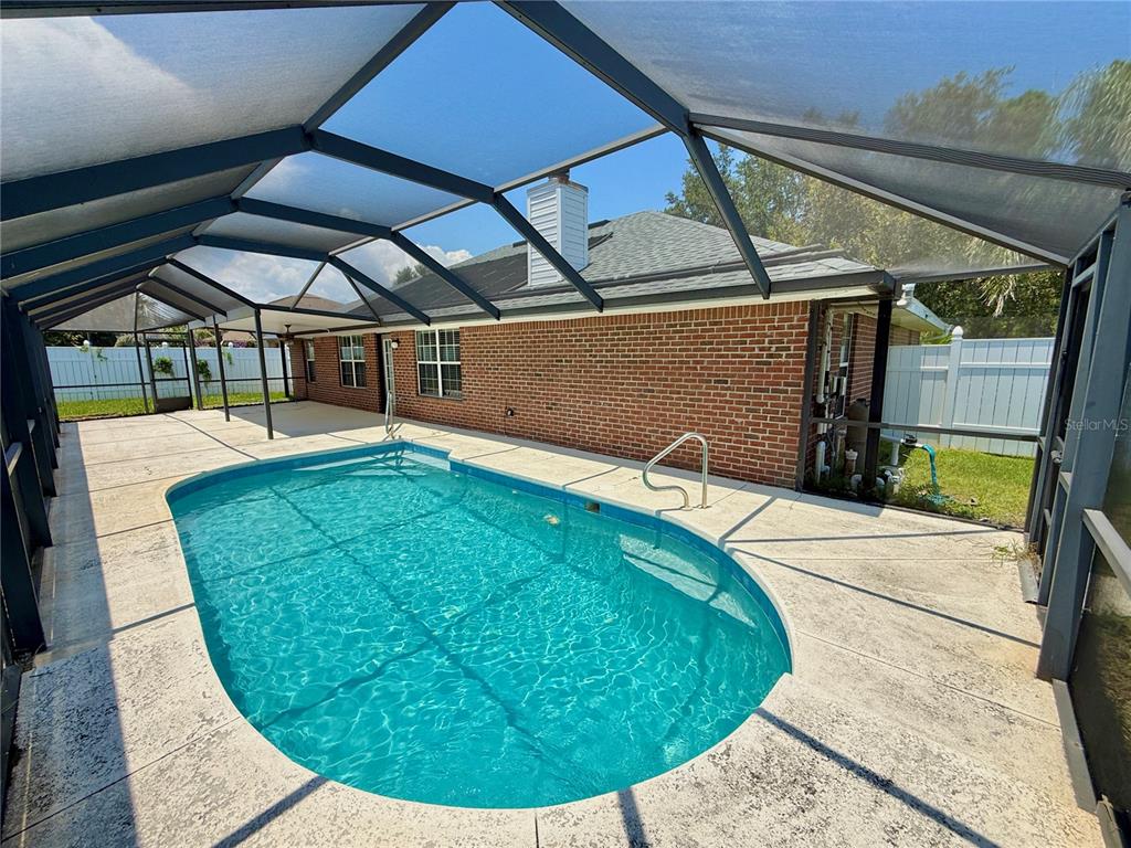 A brick house with a screened-in swimming pool and patio area in the backyard — 12 EASTMOOR LANE, PALM COAST, FL
