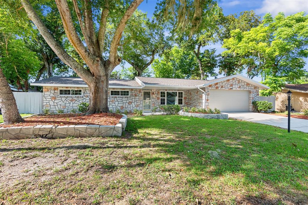 A single-story house with a stone facade, a large tree, and a front lawn — 107 WIMBLEDON COURT, PORT ORANGE, FL
