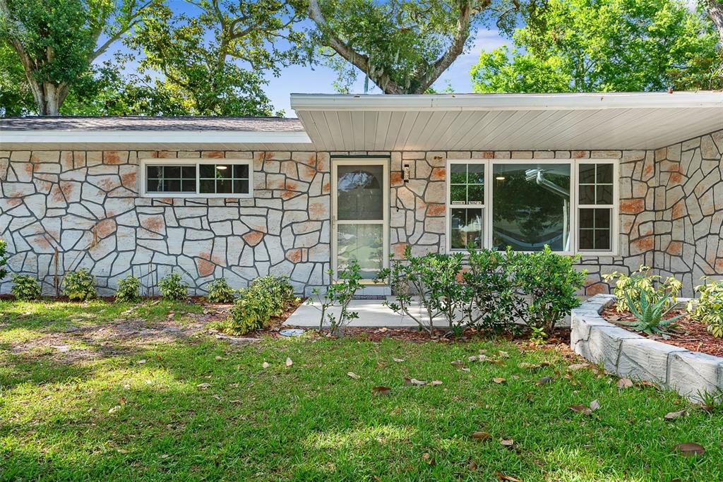 A single-story house exterior featuring a stone facade, a flat roof, and a front porch — 107 WIMBLEDON COURT, PORT ORANGE, FL