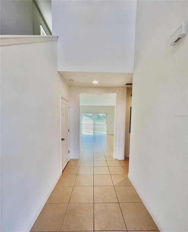 A tiled entryway leads to a hallway with a high ceiling and a sliding glass door — 124 PRIMROSE DRIVE, DAVENPORT, FL