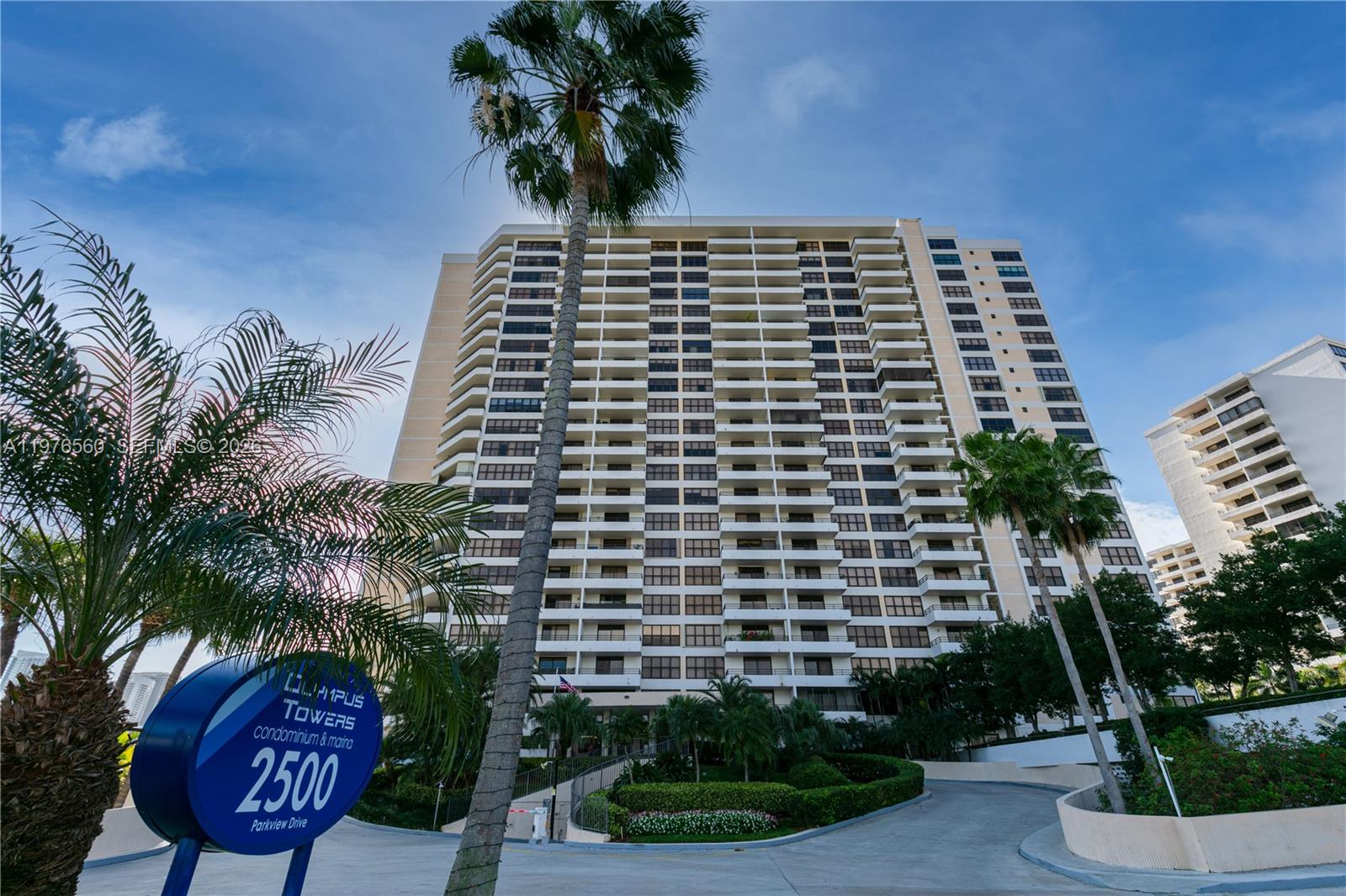 A tall residential condominium building stands behind a circular sign and palm trees — 2500 Parkview Dr # 1121, Hallandale Beach FL 33009, HALLANDALE BEACH, FL