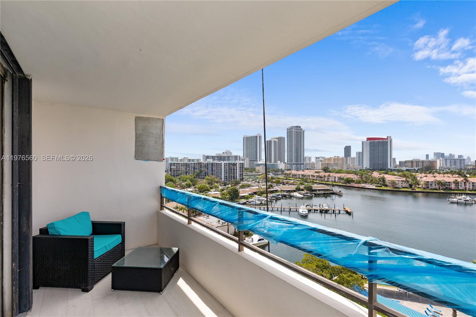 A balcony with a wicker chair, a small table, and a view of the water — 2500 Parkview Dr # 1121, Hallandale Beach FL 33009, HALLANDALE BEACH, FL