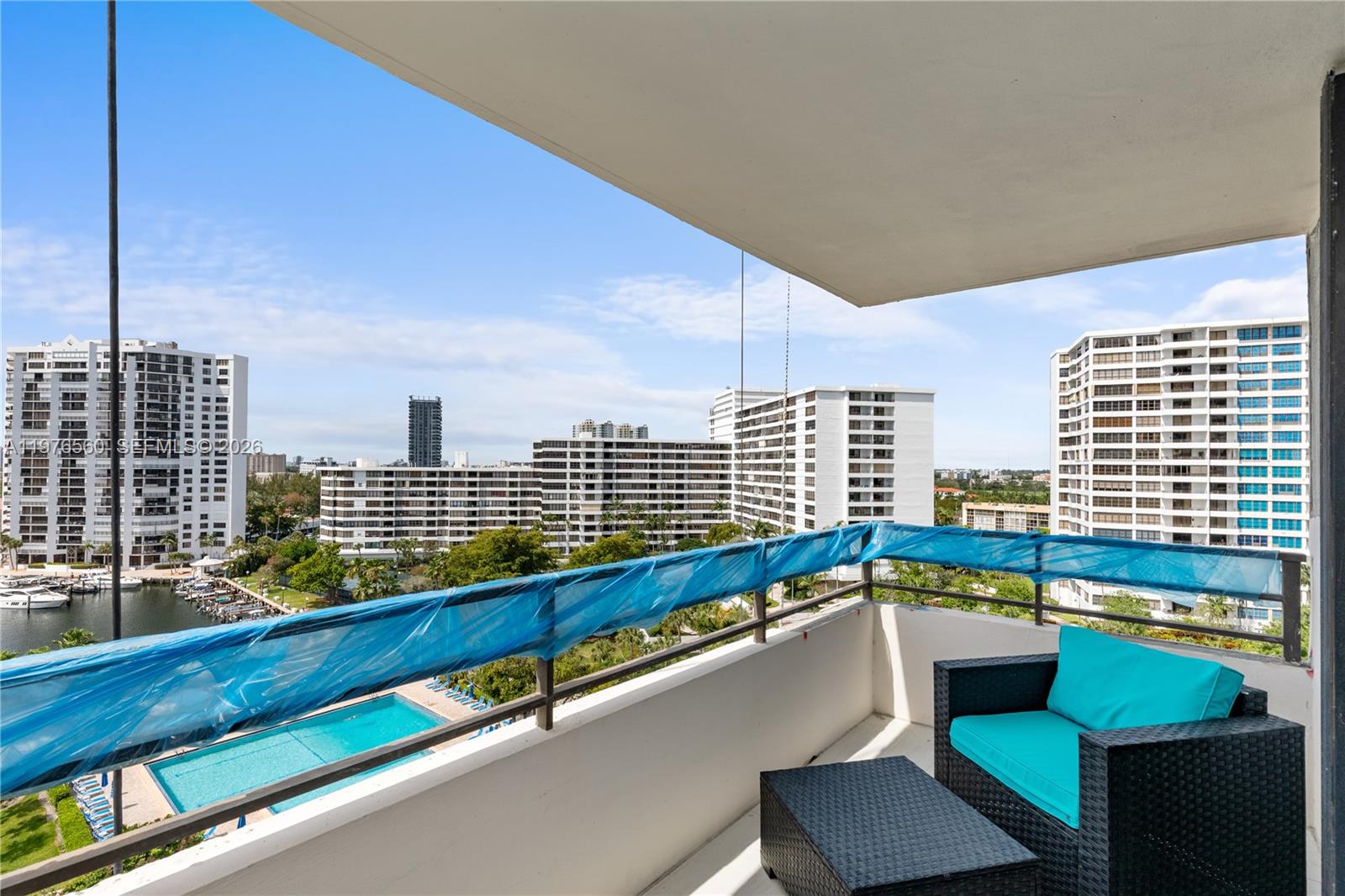A balcony with outdoor furniture overlooks a swimming pool and surrounding high-rise apartment buildings — 2500 Parkview Dr # 1121, Hallandale Beach FL 33009, HALLANDALE BEACH, FL