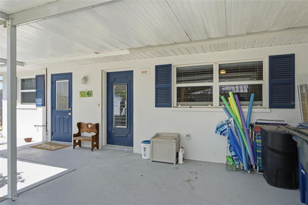 A covered patio features a white exterior wall, two blue doors, and pool noodles — 402 KETCH WAY UNIT 402, NOKOMIS, FL