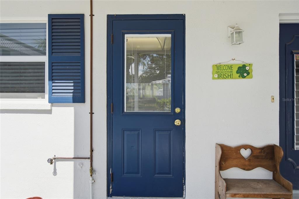 A blue door with a window and a wooden bench sit against a white wall — 402 KETCH WAY UNIT 402, NOKOMIS, FL