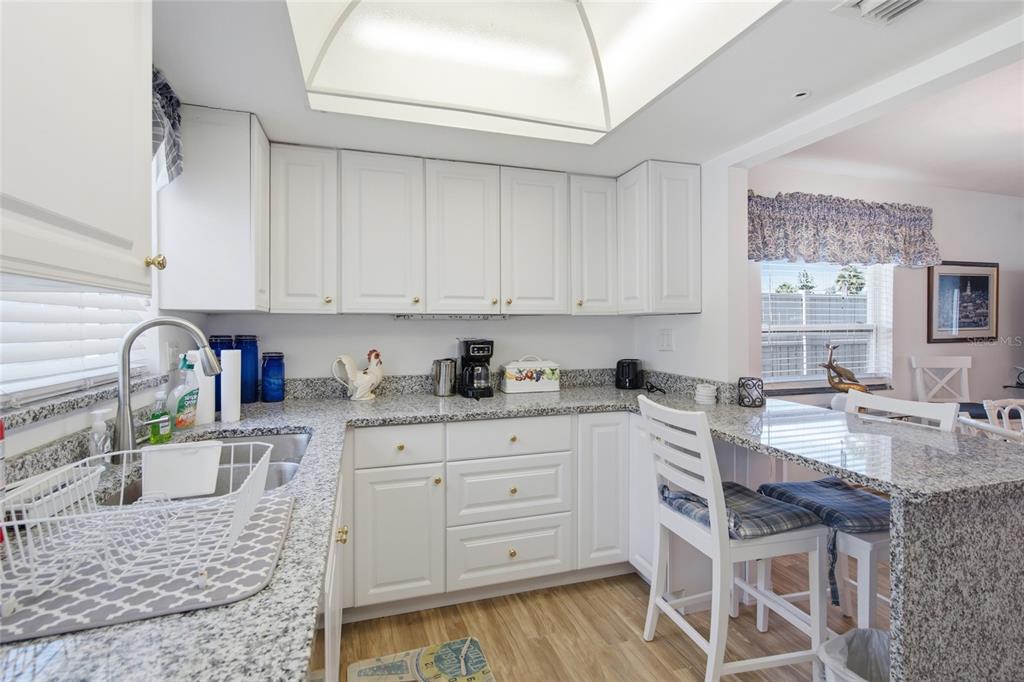 A kitchen with white cabinets, granite countertops, and a breakfast bar with two chairs — 402 KETCH WAY UNIT 402, NOKOMIS, FL