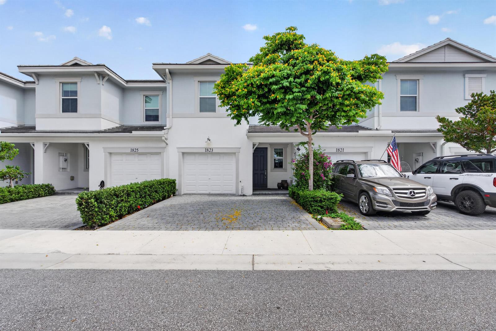 A row of three two-story townhouses with paved driveways and a large tree in front — 1823 Sandpiper Pointe Place, Deerfield Beach FL 33442, DEERFIELD BEACH, FL