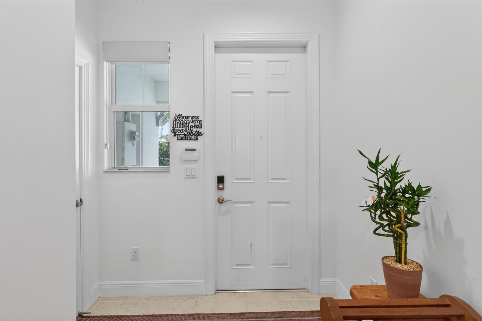 An entryway features a white door, a small window, a wall-mounted sign, and a potted plant — 1823 Sandpiper Pointe Place, Deerfield Beach FL 33442, DEERFIELD BEACH, FL
