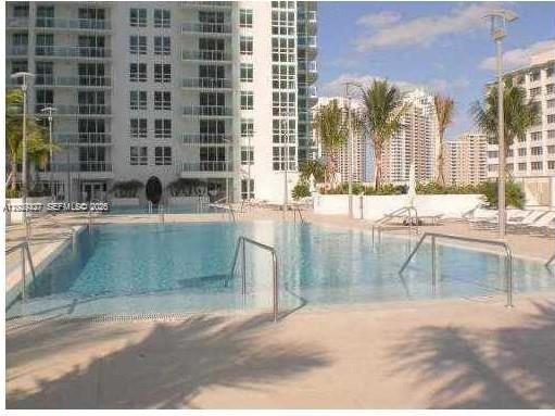 An outdoor swimming pool with metal railings sits in front of a tall residential building — 951 Brickell Ave # 1808, Miami FL 33131, MIAMI, FL